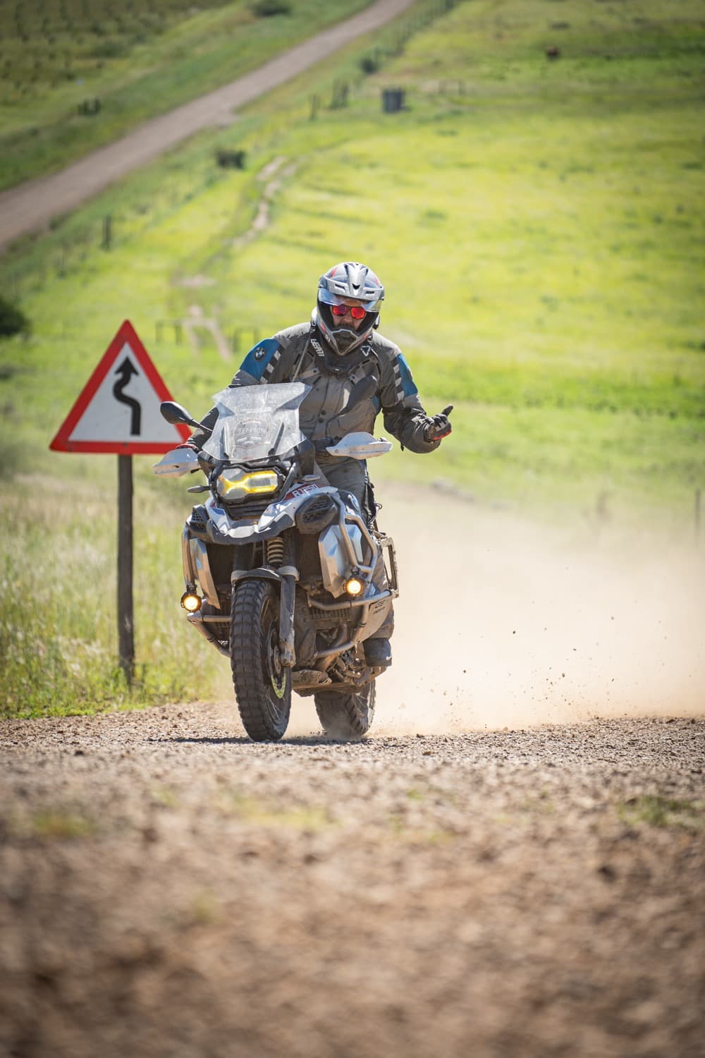Rider on a gravel road trailing dust